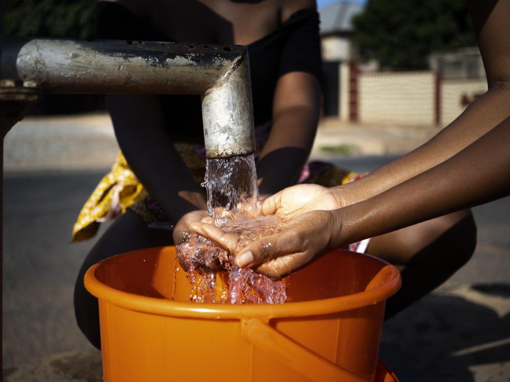african-woman-pouring-water-recipient-outdoors african-woman-pouring-water-recipient-outdoors